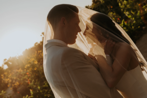 Bride and groom underneath the veil during sunset