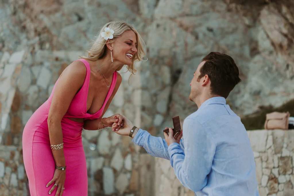 Couple laughing happily after surprise proposal at beach