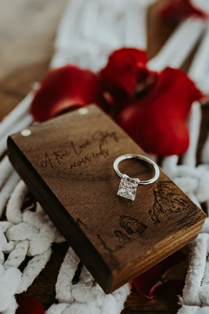 Detail shot of the engagement ring over the engraved wooden box