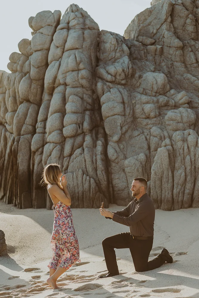 Man gets on his knees for a surprise proposal. They are on the beach
