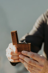 Detail shot of hands holding and engraved box with an engagement ring