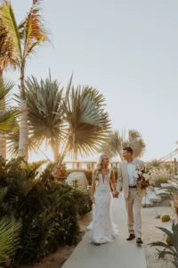Bride and Groom walk hand in hand around The Cape Hotel in Cabo San Lucas