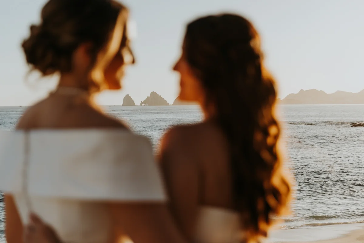 Two brides look at each other during sunset beach photos