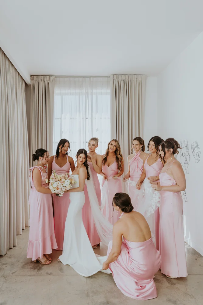Bride with bridesmaids as they help her with the dress