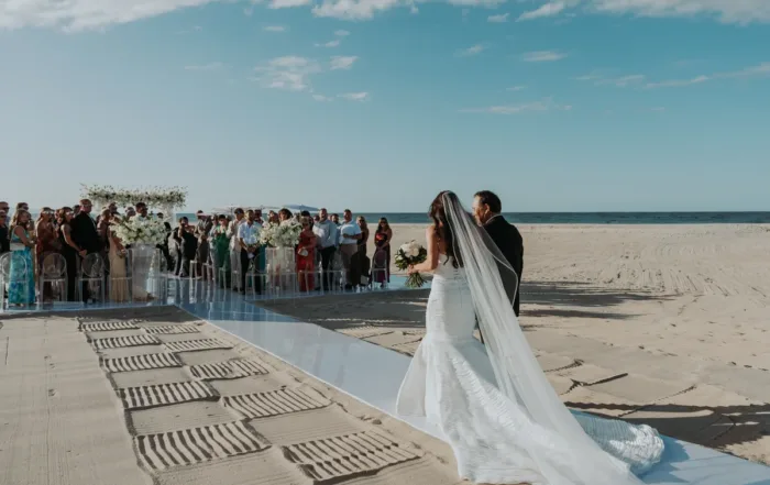 Bride walking down the aisle at beach ceremony