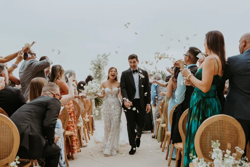 Newlyweds exit their ceremony as the guest throw flower petals