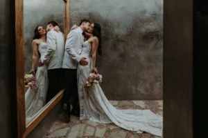Newlyweds kissing next to a mirror at ACRE Los Cabos, you can see their reflection too