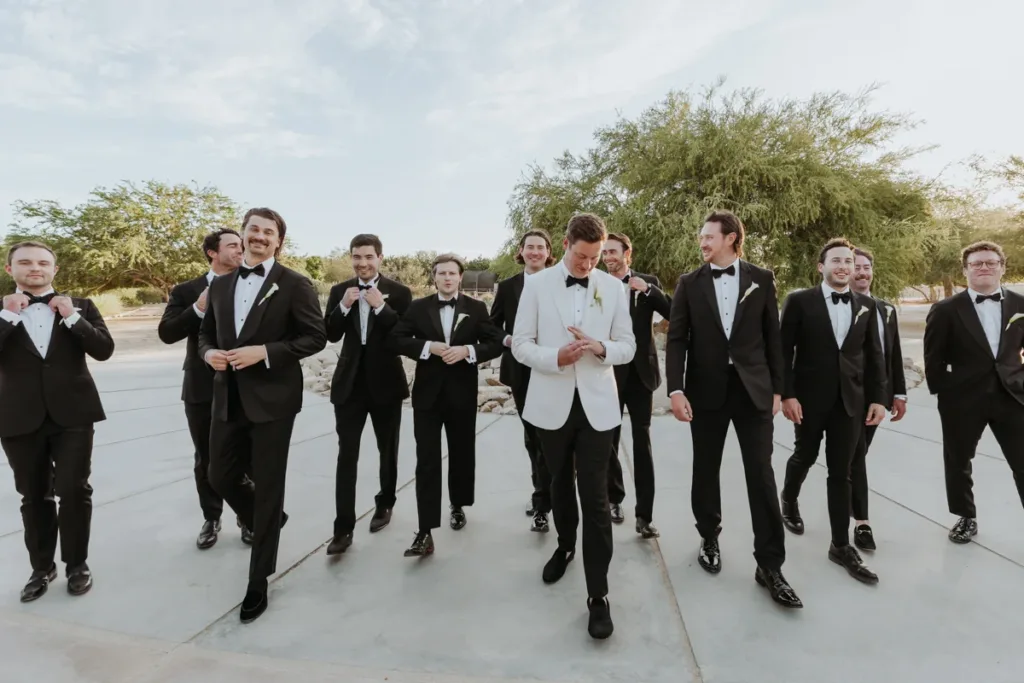 Groom walking with groomsmen and best man, they fix their wedding suits