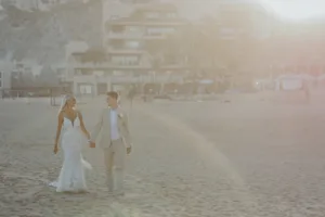 Bride and groom walking on the beach for sunset photos