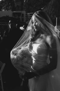 Black and white photo of the bride walking down the aisle with the veil on her face